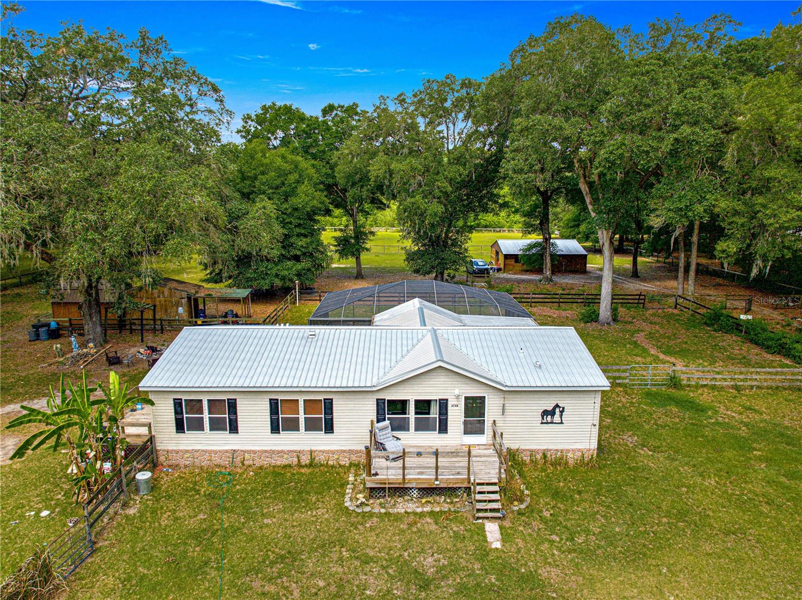 6780 NW 57th Ave aerial view showing home, screened pool, barn and paddocks
